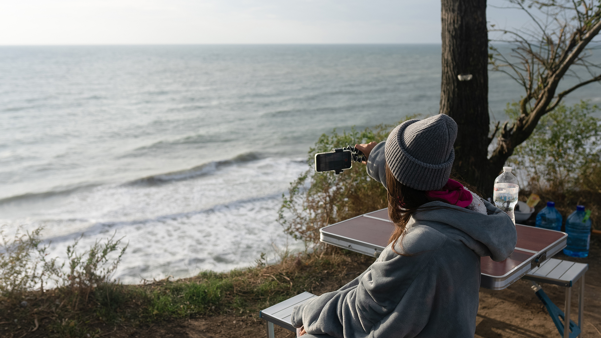 Young woman takes a photo on a smartphone of the seascape